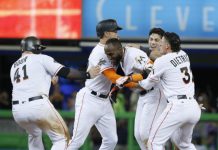 Dominicanos - Marcell Ozuna, al centro, es felicitado por sus compañeros de los Marlins de Miami, luego de disparar sencillo decisio en el noveno con el que remolcó a Dee Gordon en el partido ante los Nacionales de Washington el 19 de junio en Miami. (Fuente externa)