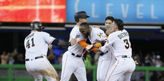 Dominicanos - Marcell Ozuna, al centro, es felicitado por sus compañeros de los Marlins de Miami, luego de disparar sencillo decisio en el noveno con el que remolcó a Dee Gordon en el partido ante los Nacionales de Washington el 19 de junio en Miami. (Fuente externa)